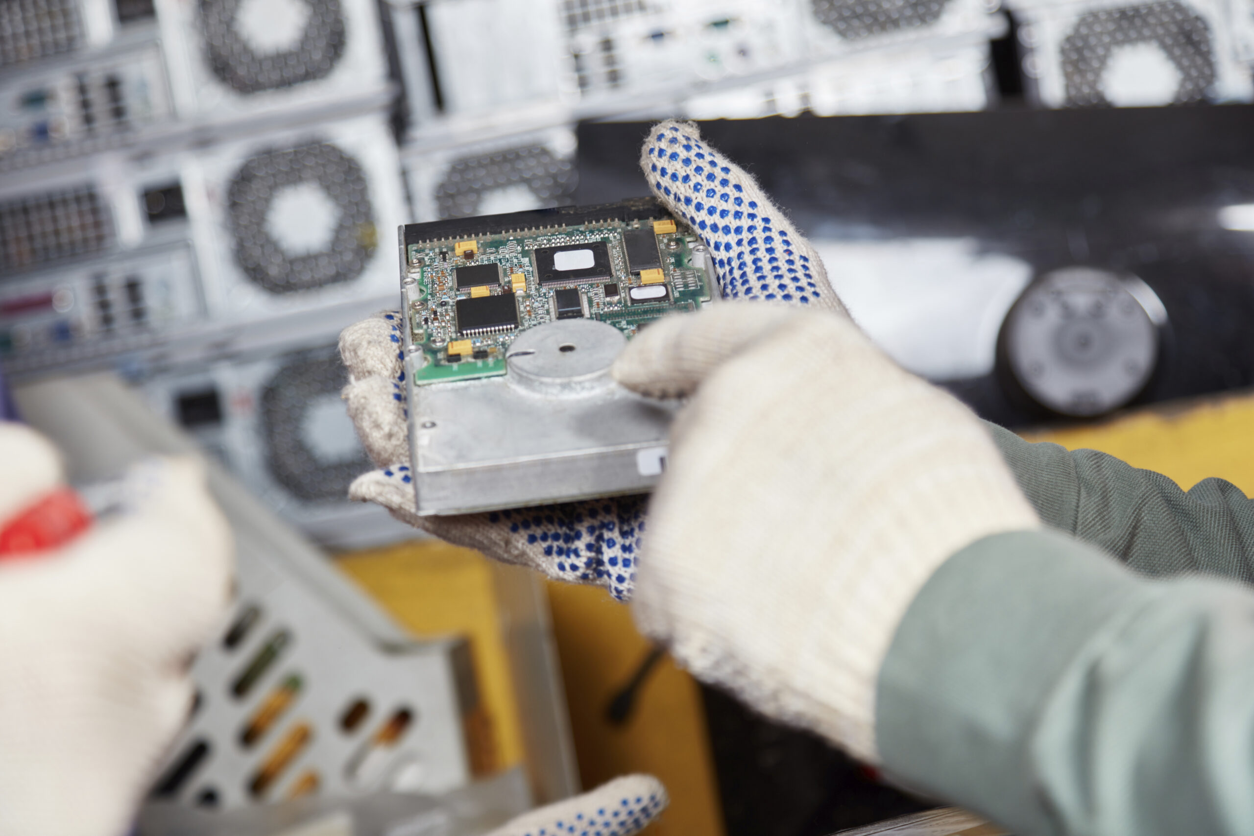 Worker holding hard disk in computer recycling plant